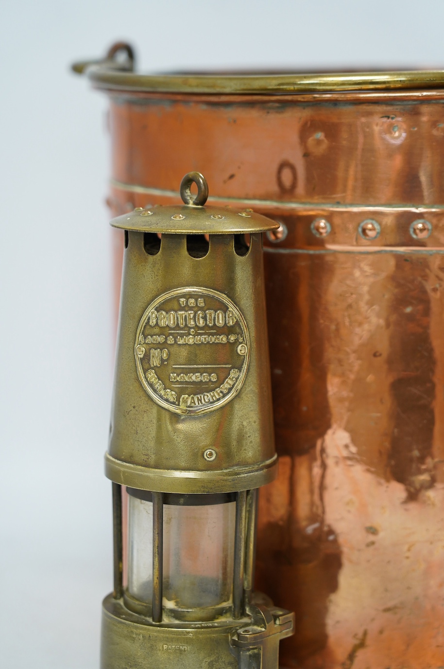 A brass handled copper coal bin and The Protector brass miner’s lamp, coal bin 30cm high. Condition - coal bin has some minor dents, miner’s lamp good